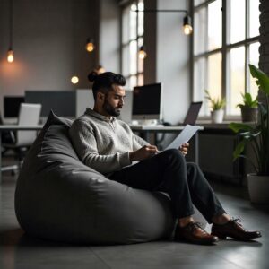 Un salarié regarde son ordinateur confortablement assis dans un coussin type fat boy.
