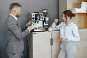 Deux salariés papotent autour de la machine à café de leur entreprise.